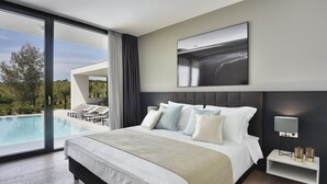 Une chambre d’hôtel moderne avec un grand lit, une vue sur une piscine et un tableau au mur.