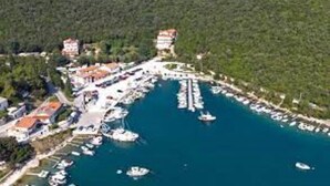 An aerial view of a marina with boats docked, surrounded by lush greenery and buildings with red roofs. - Beautiful new Villa with private pool ideal for vacation for couples or a family (Krnica)