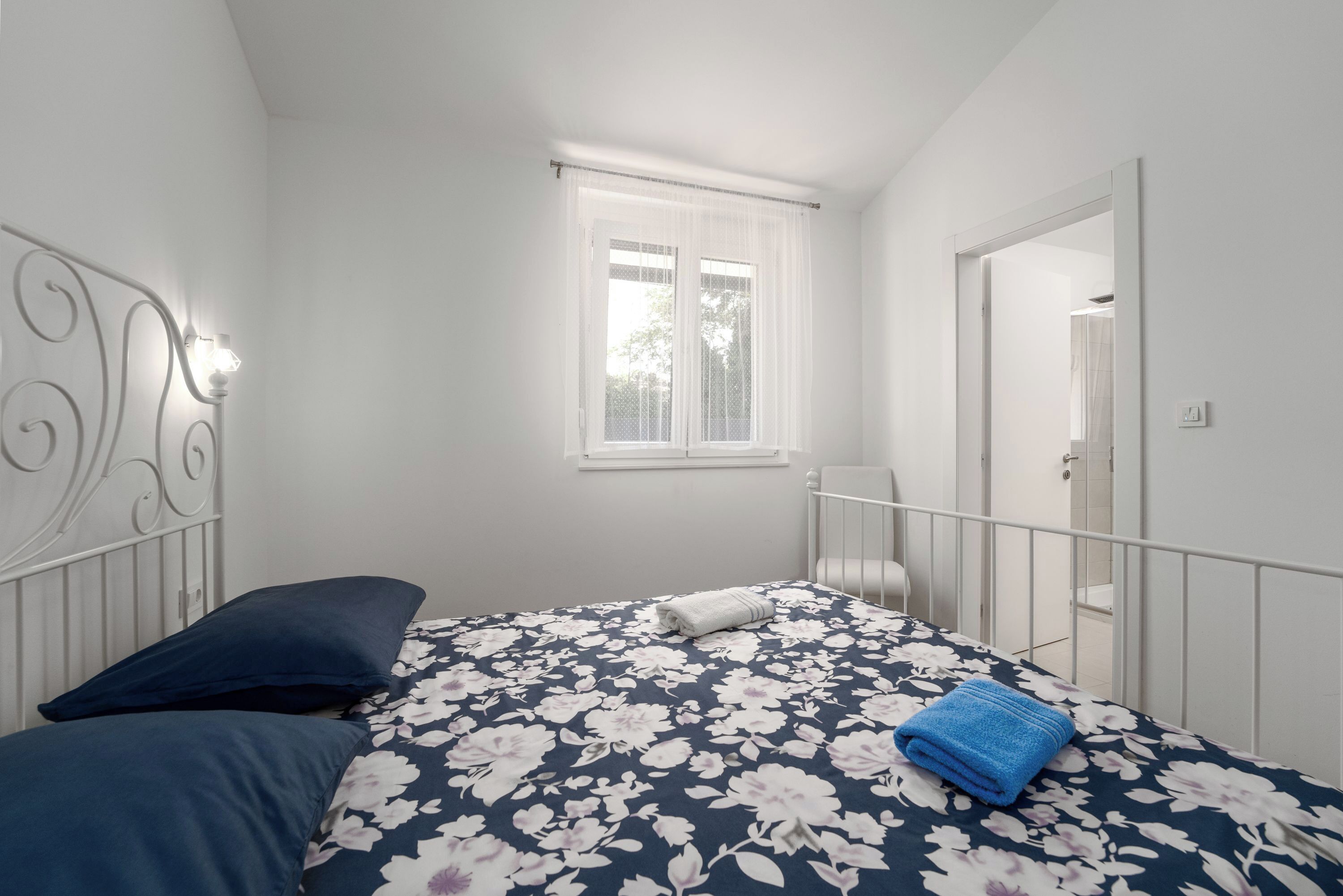 A bedroom with a bed, a window, and a door.