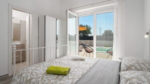 A bedroom with a bed, a balcony with a chair, and a view of a swimming pool. - Beautiful new Villa with private pool ideal for vacation for couples or a family (Krnica)
