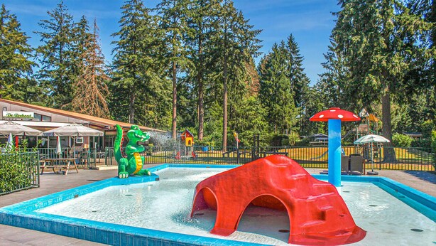 Ein Wasserspielbereich mit Rutsche und Dinosaurier-Statue.