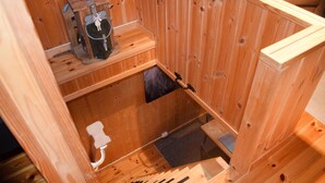 Una sauna in legno con una panca di legno, una panca con un asciugamano e un piccolo armadietto in legno.