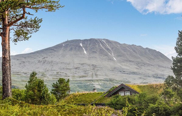 A mountain with a small cabin in the foreground.