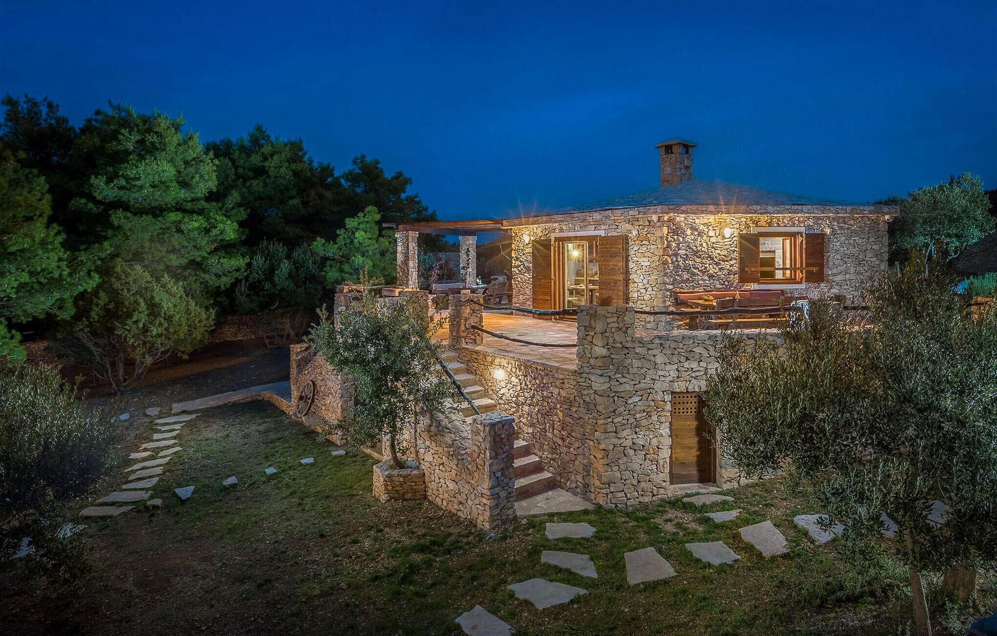 A stone house with a stone staircase leading to a wooden deck.