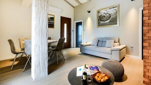 A modern living room with a grey sofa, a round coffee table with a bottle and glasses, and a patterned ottoman. - Lovely home in Policnik with sauna (Policnik)