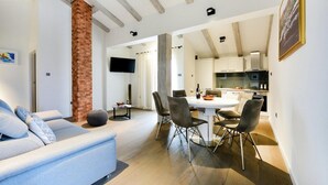 A modern living room with a sofa, a dining table with chairs, and a kitchen area visible through an open door. - Lovely home in Policnik with sauna (Policnik)