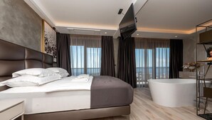 Habitación de hotel moderna con una cama grande, una bañera independiente y vistas a la ciudad.