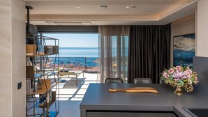 Una habitación moderna con vistas al mar, una zona de comedor con un bate de madera y un jarrón de flores.