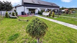 Una casa moderna con un patio amplio, una hamaca y un césped cuidado.