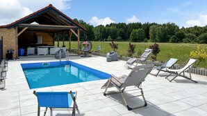 Una piscina con sillas de descanso y una zona de estar techada.