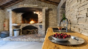 A rustic interior with a stone fireplace, a wooden table with a bowl of cherries and a martini glass, and a brick wall. - 8 bedroom beautiful home in Zaton (Zaton)