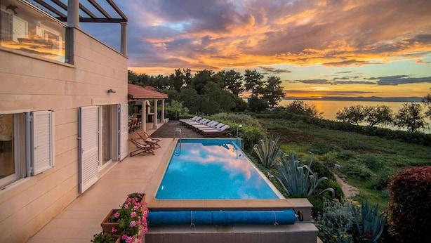 A modern house with a swimming pool, outdoor seating, and a view of the sunset over a body of water. - Beautiful home in Mirca (Mirca)