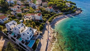 An aerial view of a coastal residential area with modern houses, a clear blue sea, and a sandy beach. - Stunning home in Sutivan with sauna (Sutivan)