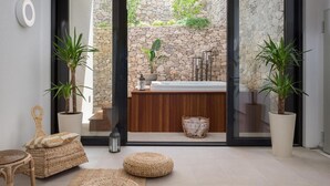 A modern bathroom with a stone wall, a wooden vanity, and a large bathtub. - Stunning home in Sutivan with sauna (Sutivan)