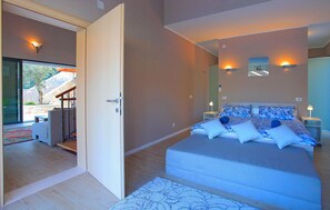 Relax in a serene bedroom with a large bed, two bedside tables, and a door leading to a scenic outdoor area.