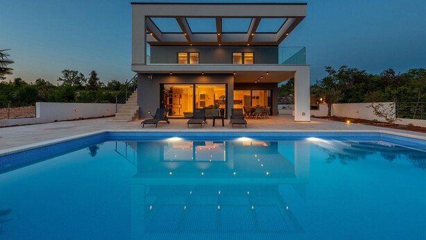 Ein modernes, zweistöckiges Haus mit Schwimmbecken vor der Fassade.