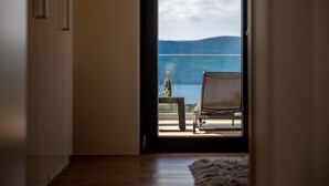 Ein Zimmer mit Blick auf einen Balkon, ein Sessel und eine Champagnerflasche auf einem kleinen Tisch.
