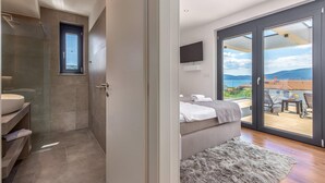 Ein modernes Badezimmer mit Duschkabine aus Glas, integriertem Waschbecken und einem großen Fenster.