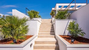 Eine Treppe führt zu einem modernen Gebäude mit weißen Wänden und großen Fenstern.