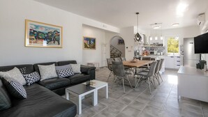 A modern living room with a black leather sofa, a dining table with chairs, and a kitchen area with a refrigerator and microwave. - Beautiful home in Makarac (Makarac)