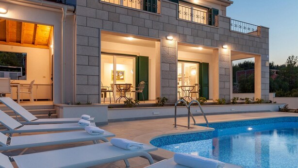 A modern two-story house with a swimming pool, outdoor seating, and a well-lit entrance. - Beautiful home in Makarac (Makarac)