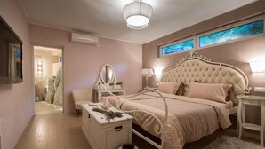Un dormitorio con una cama grande, mesitas de noche, un tocador con espejo y un candelabro.