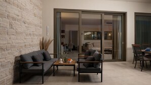 A modern living room with a stone wall, two sofas, a coffee table, and a dining area with chairs. - Nice home in Smokovic (Smokovic)