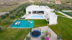 A modern house with a swimming pool, outdoor seating, and a trampoline. - Nice home in Smokovic (Smokovic)