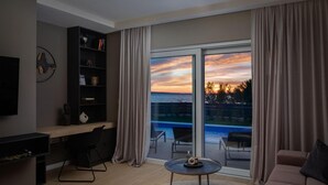 Un moderno salón con un amplio ventanal corredera que da a un balcón con vista a la piscina.