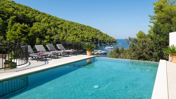 Ein Pool mit Liegestühlen und Blick auf das Meer.