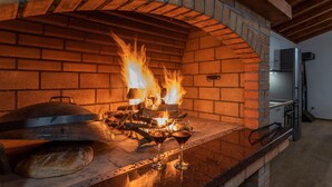 Ein Backofen mit Flammen, ein Pizzaschieber und zwei Gläser Rotwein auf einer Arbeitsplatte.