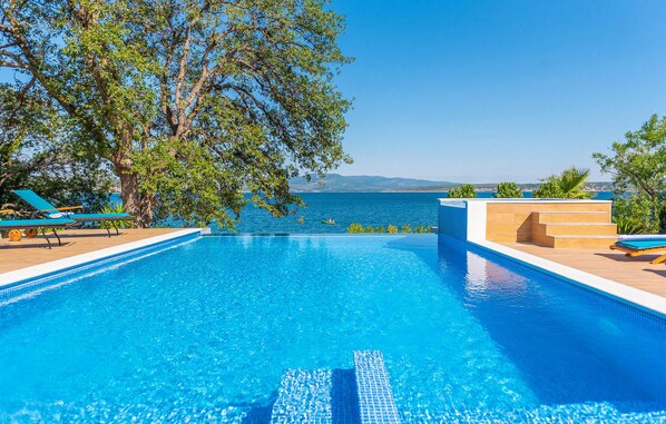 Relax by the serene pool surrounded by lush greenery and a stunning sea view.
