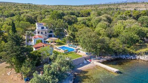 Eine Villa mit Swimmingpool, umgeben von üppiger Vegetation und einer Bergkulisse.