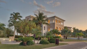 A modern hotel with a central courtyard, palm trees, and a well-maintained lawn. - Charming Studio for 4 people with balcony, Wi-Fi, AC & pool access in Cap Cana (Punta Cana)