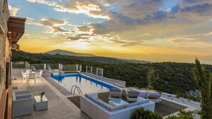 Un área de piscina en la azotea con sillas de descanso y vistas al paisaje.
