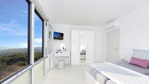 Ein modernes Schlafzimmer mit großem Fenster, einem Bett, einem Schminktisch mit Spiegel und einem Kleiderschrank.