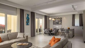 Een moderne woonkamer met een bank, salontafel en een eethoek met stoelen en een tafel.