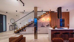 Una cocina moderna con una isla central, una escalera de madera y un comedor con sillas de cuero.