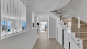 Un interior moderno con una escalera, un comedor y vistas al mar.