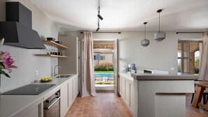 A modern kitchen with a central island, a built-in oven, and a view of an outdoor pool area. - Amazing home in Sv. Lovrec (Sv. Lovrec)