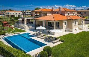 Una propiedad residencial con piscina, mobiliario de exterior y zona de juegos.