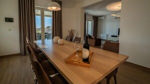 Un comedor moderno con una mesa de madera, sillas y una botella de vino sobre una bandeja.