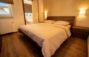 A bedroom with a wooden bed, beige bedding, and two wall-mounted lights. - Awesome home in Kastelir with private swimming pool, can be inside or outside (Kastelir)