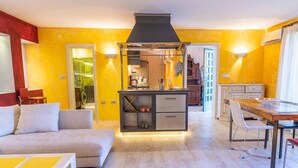 Une cuisine moderne dotée d’un îlot central, un coin repas avec une table et des chaises, et un espace de vie comprenant un canapé et une table basse.