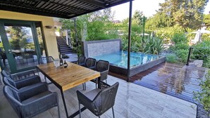 Un espace extérieur abrité comprenant une piscine, des sièges et un escalier menant à un niveau supérieur.