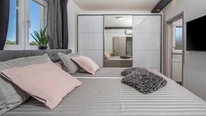 Une chambre moderne avec un grand lit, un canapé, une télévision et une porte coulissante donnant sur une salle de bain.