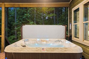 Ein Whirlpool mit Holzterrasse und Blick auf einen Wald.