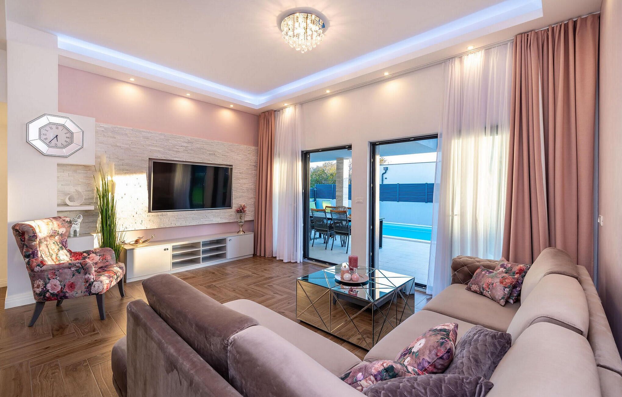 A modern living room with a flat-screen TV, comfortable sofas, a coffee table, and a view of the outdoors.