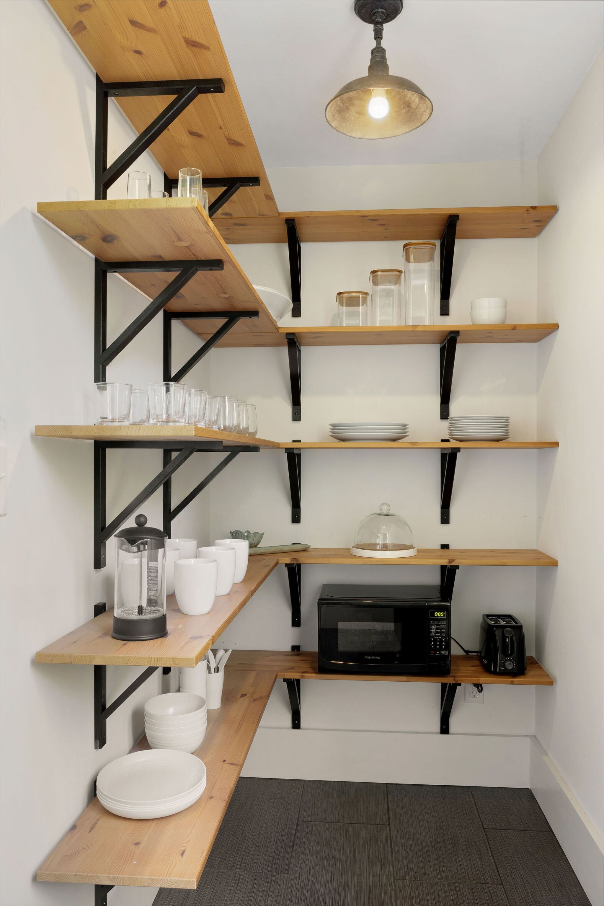Una cucina con mensole in legno, un forno a microonde e un tostapane.