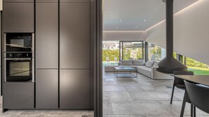Una cocina moderna con electrodomésticos integrados y vistas a una piscina y zona de estar exterior.